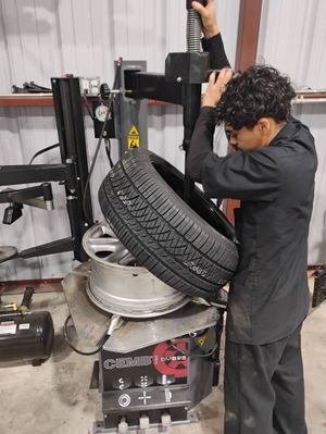 Mechanic using a tire machine to remove a tire from a wheel in a garage.