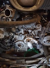 Engine bay with various components; water pump visible, dark colors, tools nearby.