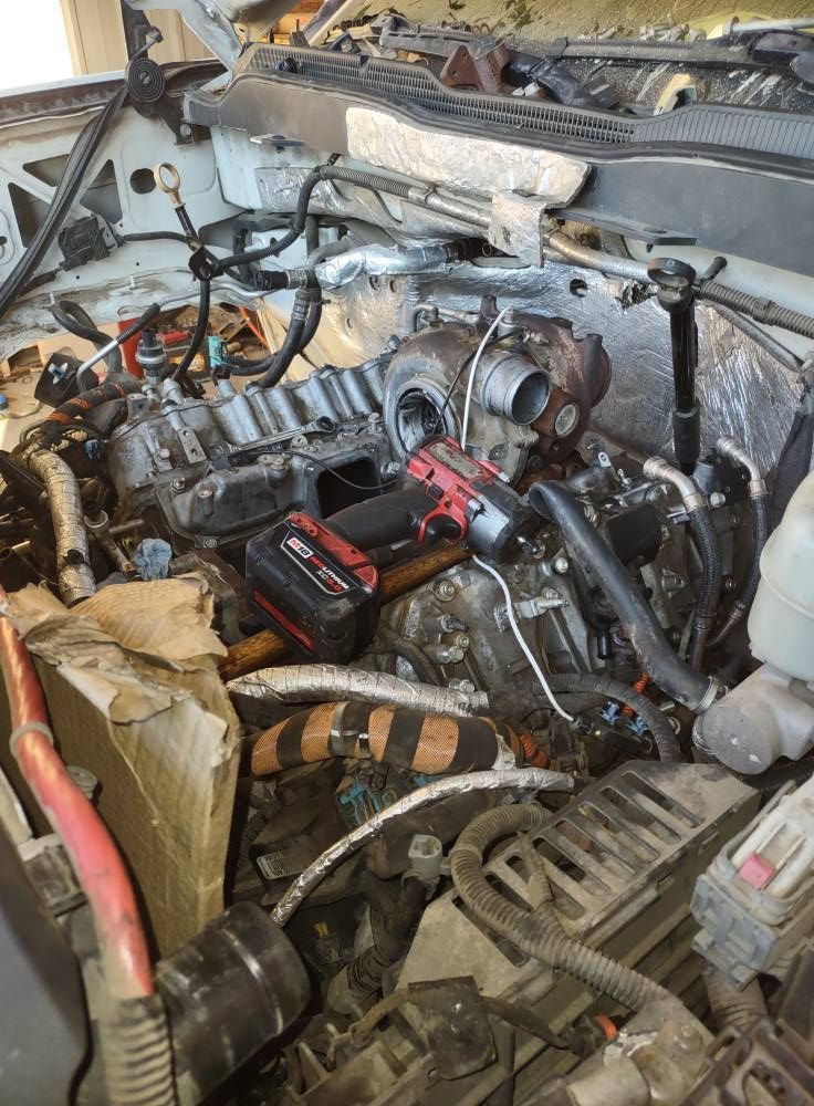 Open truck engine bay with turbocharger, tools, and exposed components.
