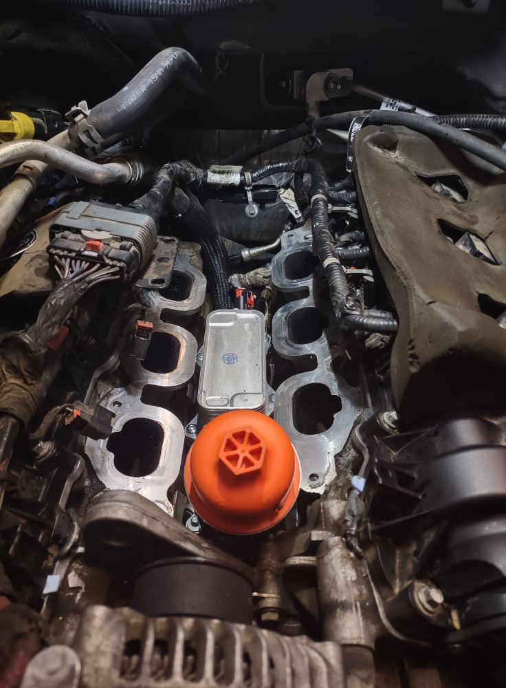 Engine bay with intake manifold removed, showing engine components and an orange oil filter.