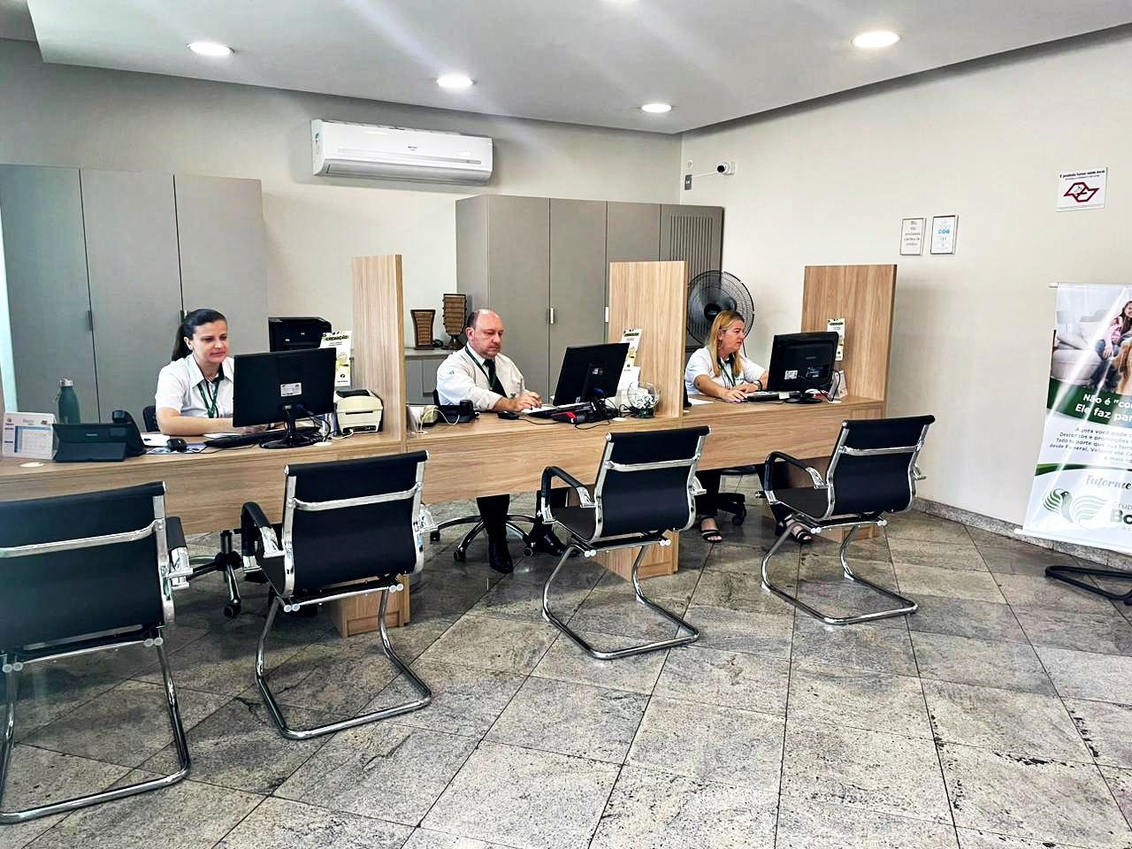 Um grupo de pessoas está sentado em mesas de um escritório.