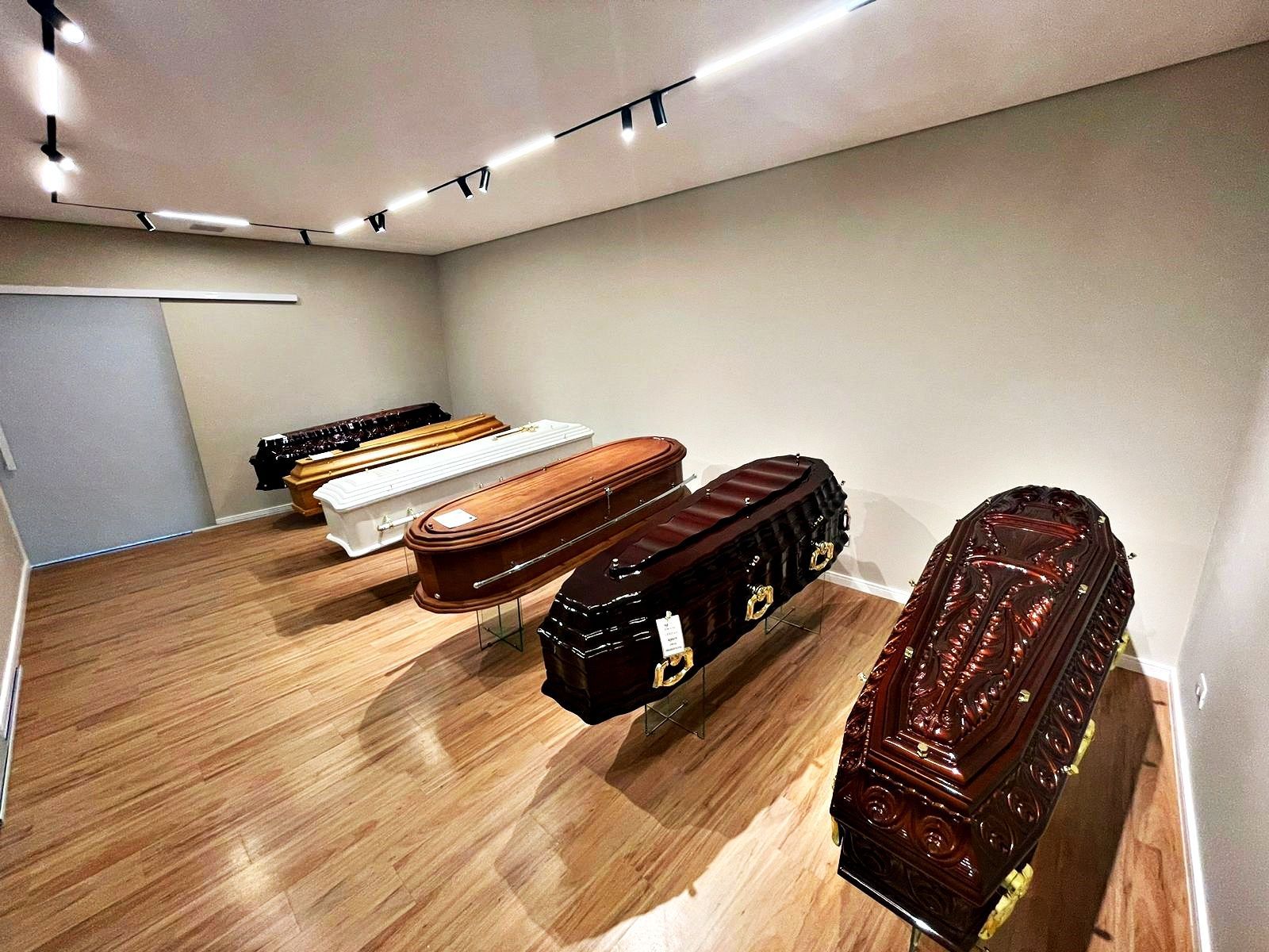 Uma fileira de caixões estão alinhados em uma sala