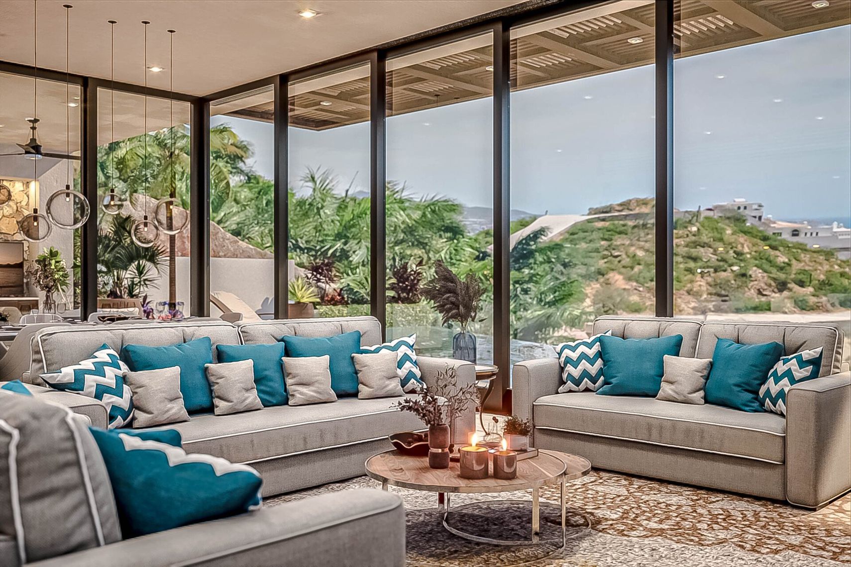 A living room with two couches , a table , and a lot of windows with a beautiful ocean view.