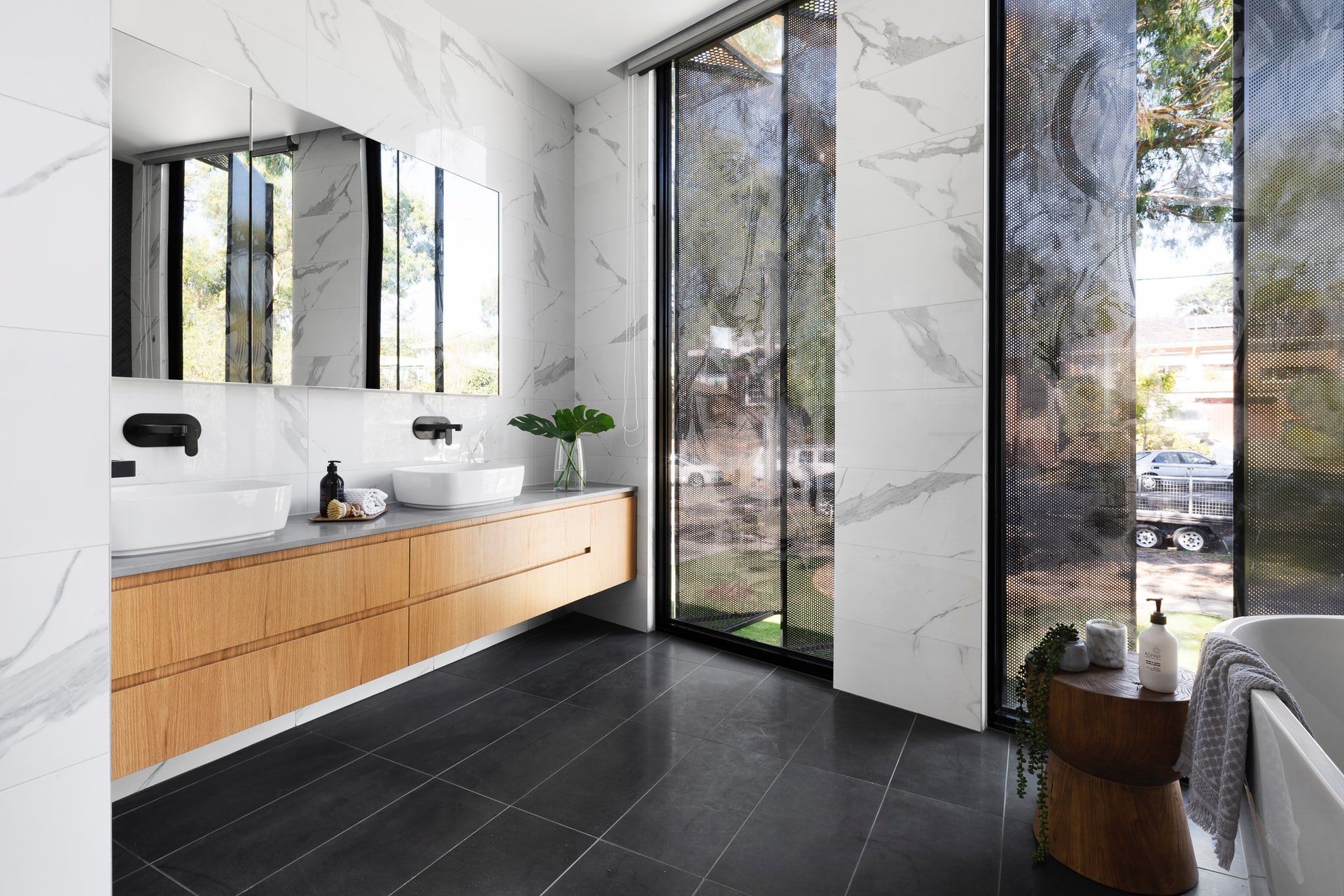 A bathroom with two sinks , a tub , and a large window.