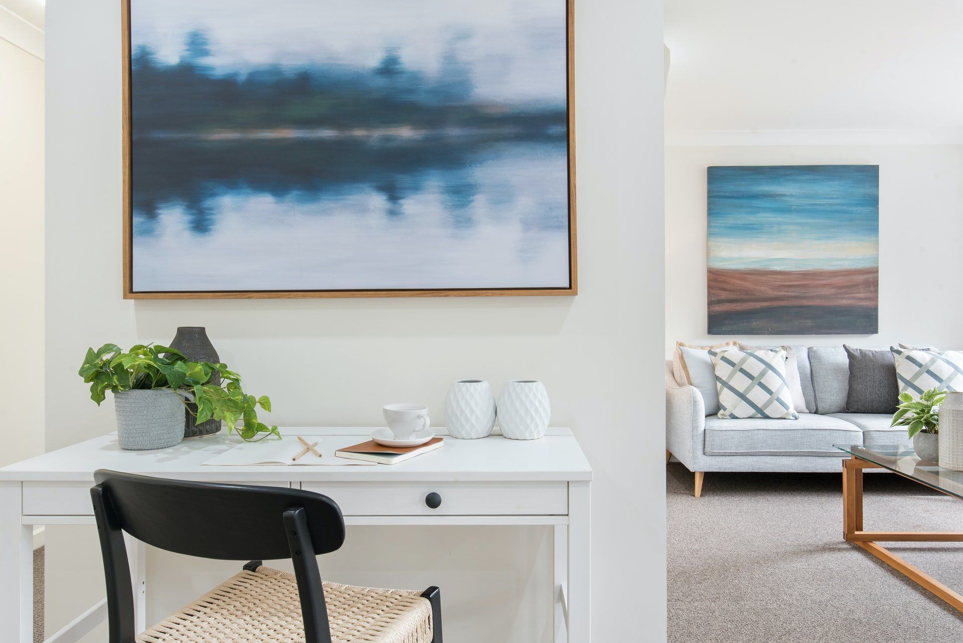 There is a painting on the wall above the desk in the living room.