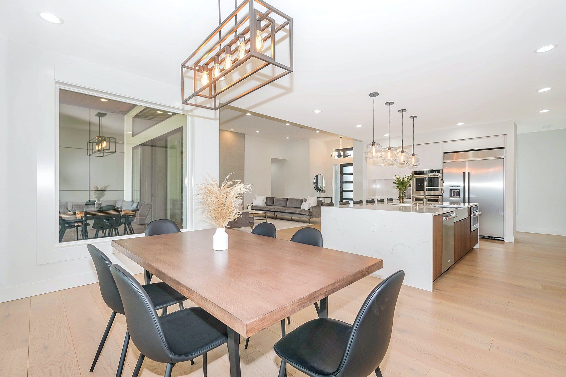 A dining room table and chairs in a house with a large window.