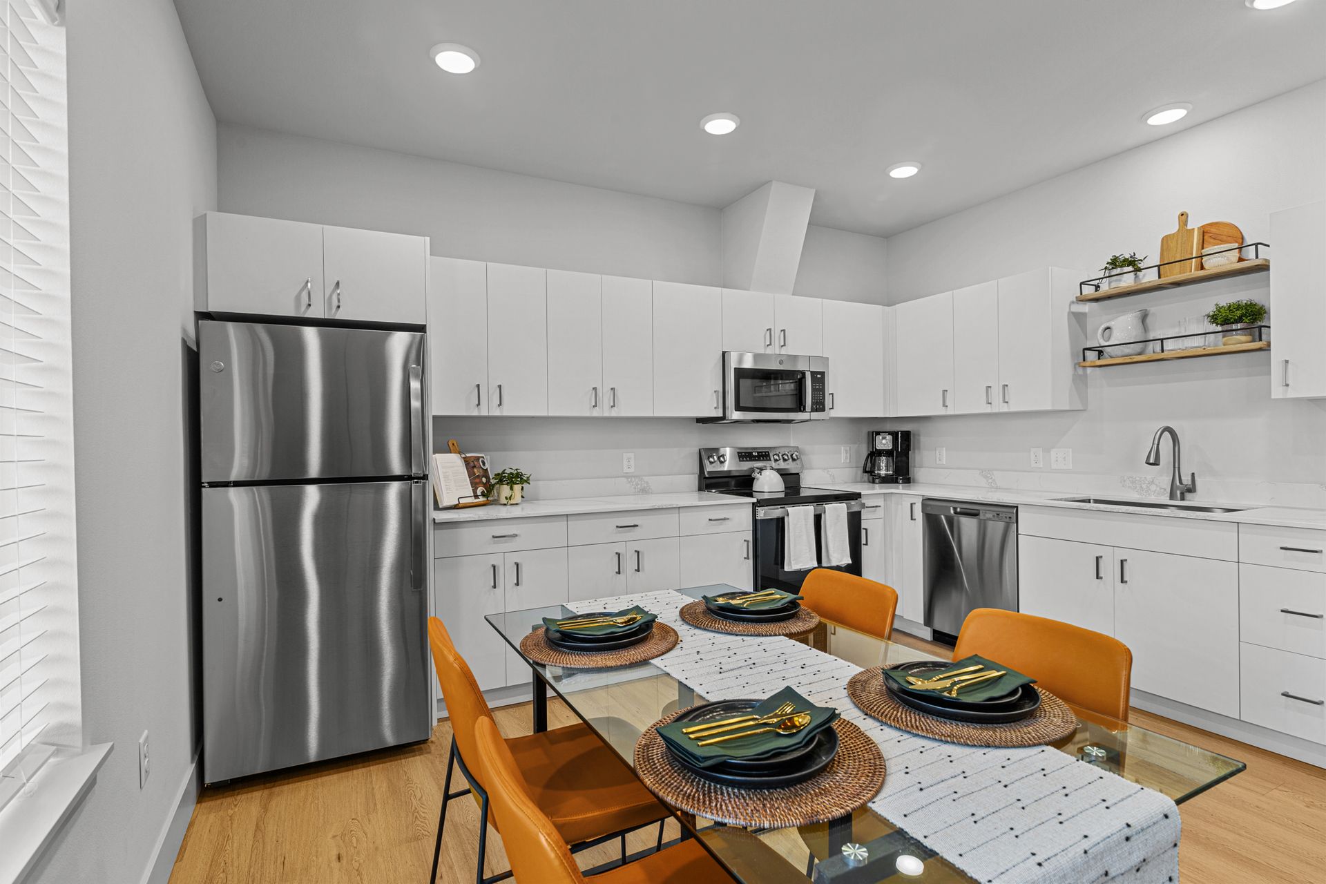 An empty apartment with a kitchen , living room , and stainless steel appliances.
