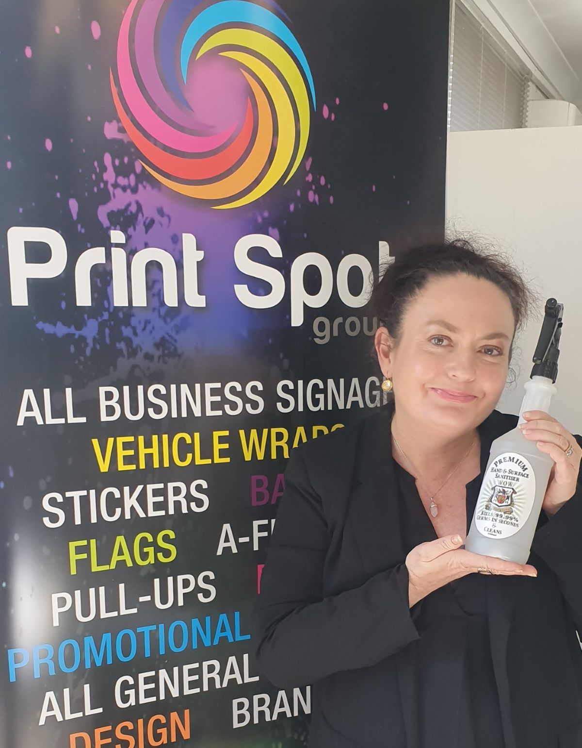 A Woman Holding a Bottle in Front of a Sign — Print Spot Group in Byron Bay, NSW