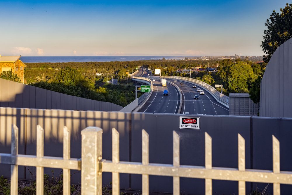 Highway With Traffic, Seen From Behind a Gray Fence — Print Spot Group in Tweed Heads, NSW