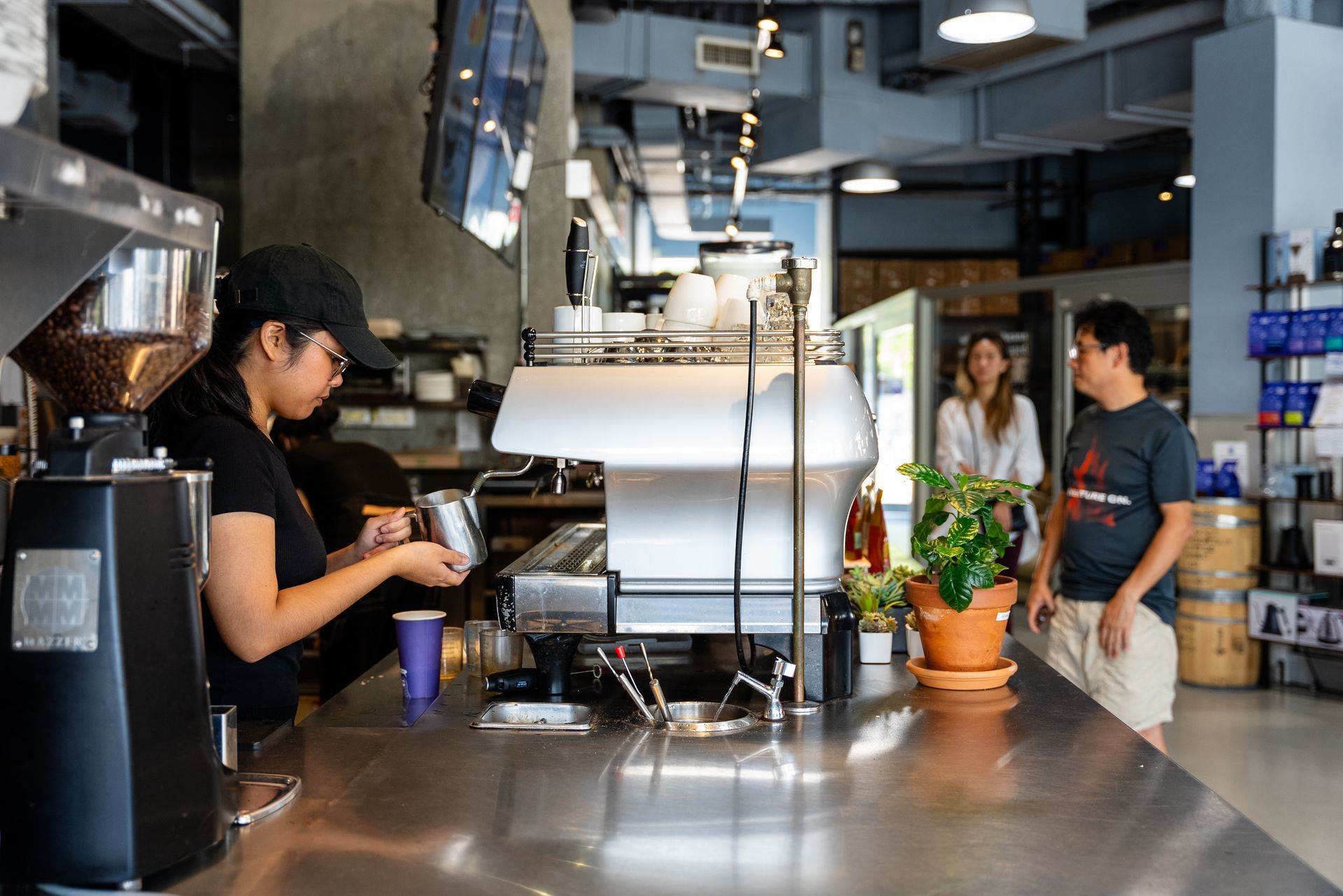 A woman is making a cup of coffee in a coffee shop.