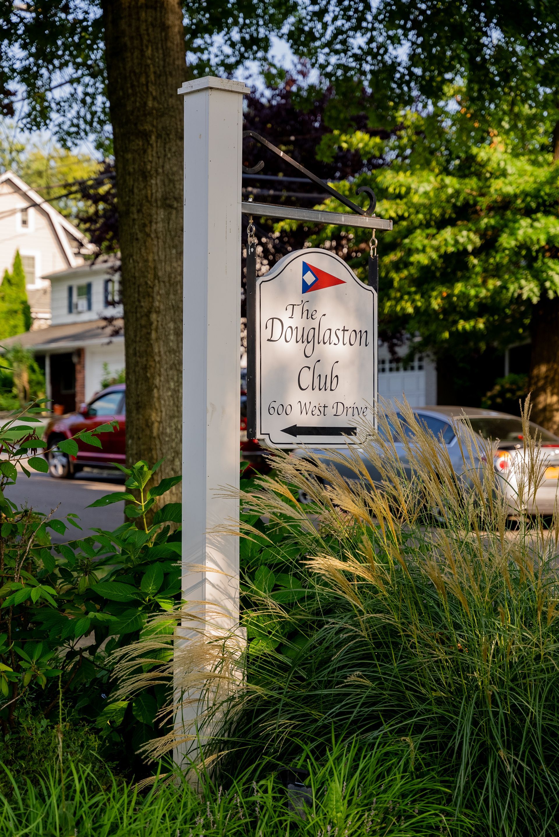 A white pole with a sign on it in front of a house.