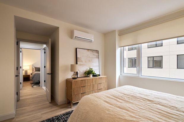 A bedroom with a bed , dresser , window and air conditioner.