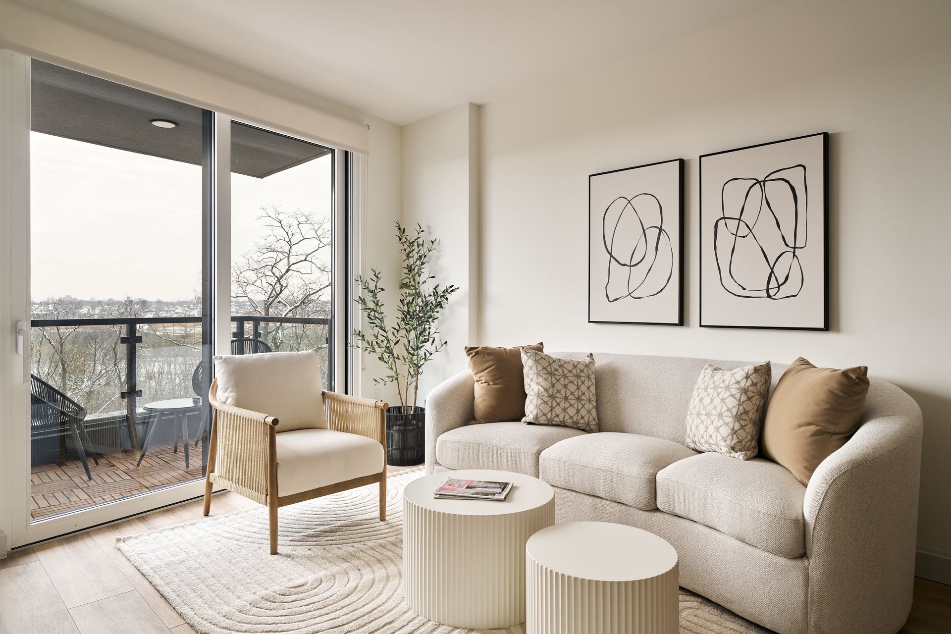 A living room with a couch , chair , tables and a balcony.