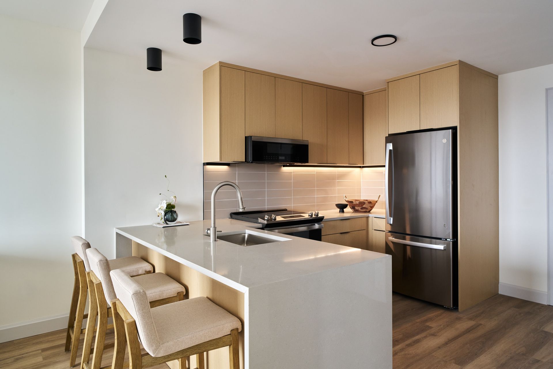 A kitchen with wooden cabinets , stainless steel appliances , a refrigerator and a sink.