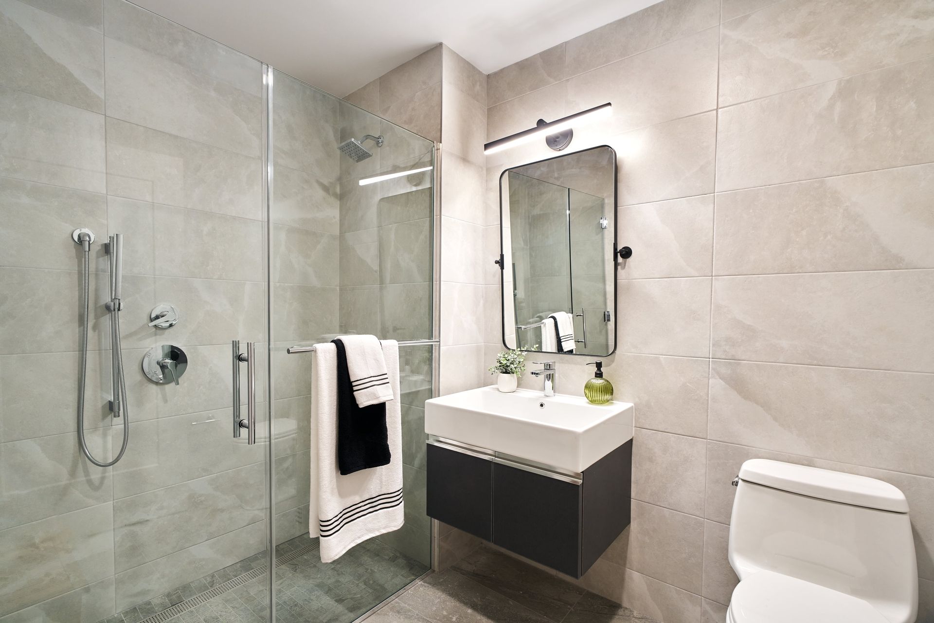 A bathroom with a sink , toilet , shower and mirror.