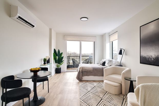 A living room with a bed , chairs , a table and a television.