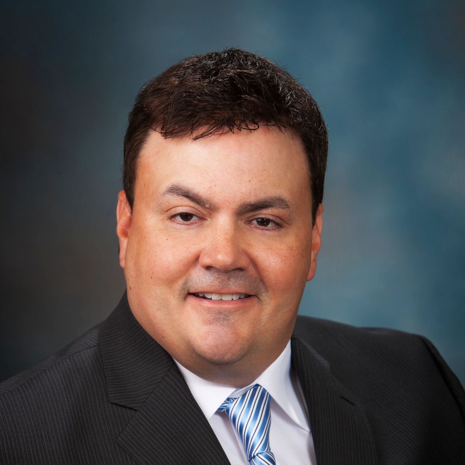 A man in a suit and tie is smiling for the camera