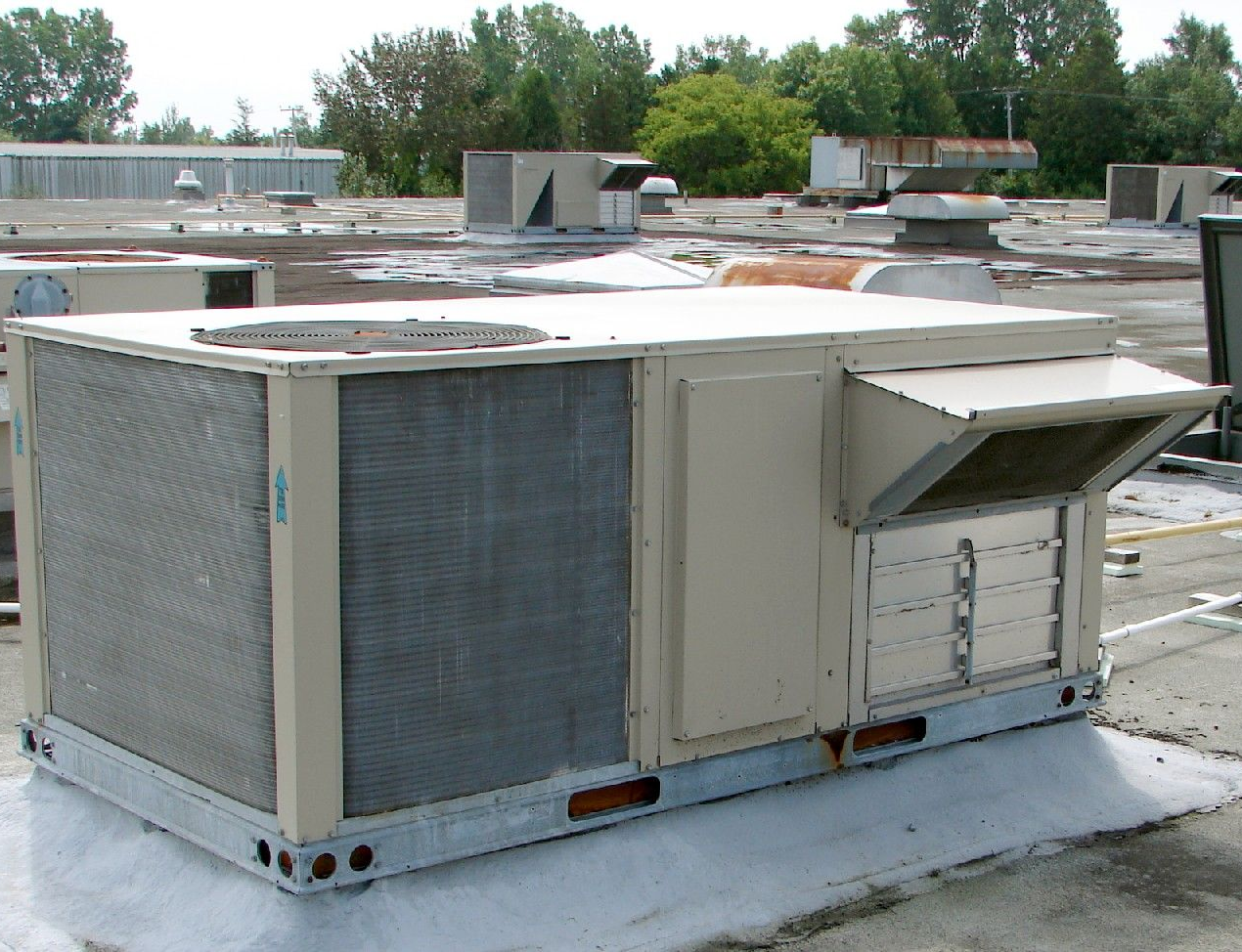 Commercial rooftop HVAC unit with metal vents and ductwork on a flat roof