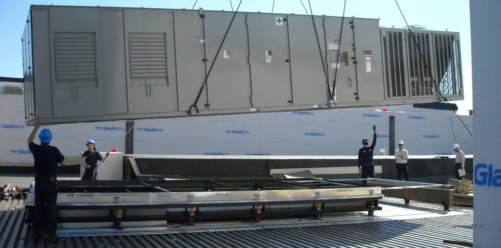 A man in a blue hard hat is lifting a large box