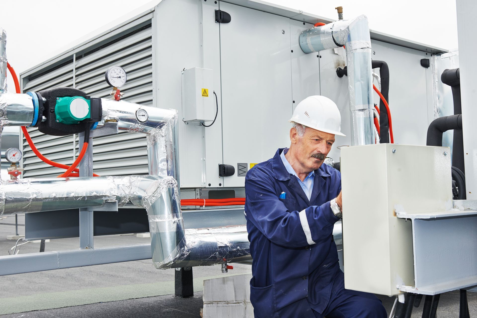 an elderly technition works on a rooftop HVAC unit, he knows how long commercial HVAC systems last