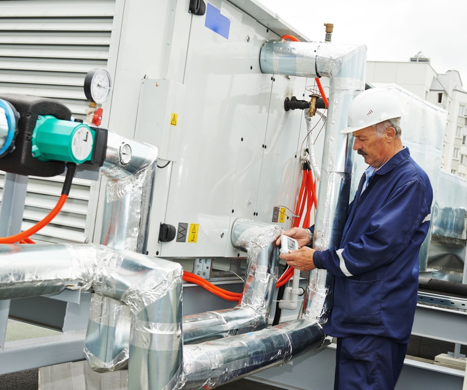 the elderly technition uses a diagnostic tool to help him identify problems with the HVAC unit