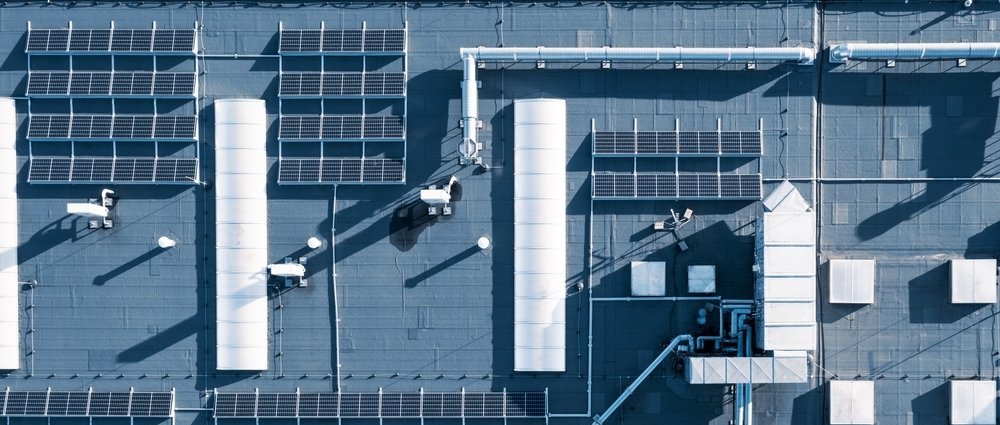 An aerial view of a building with a lot of solar panels on the roof.