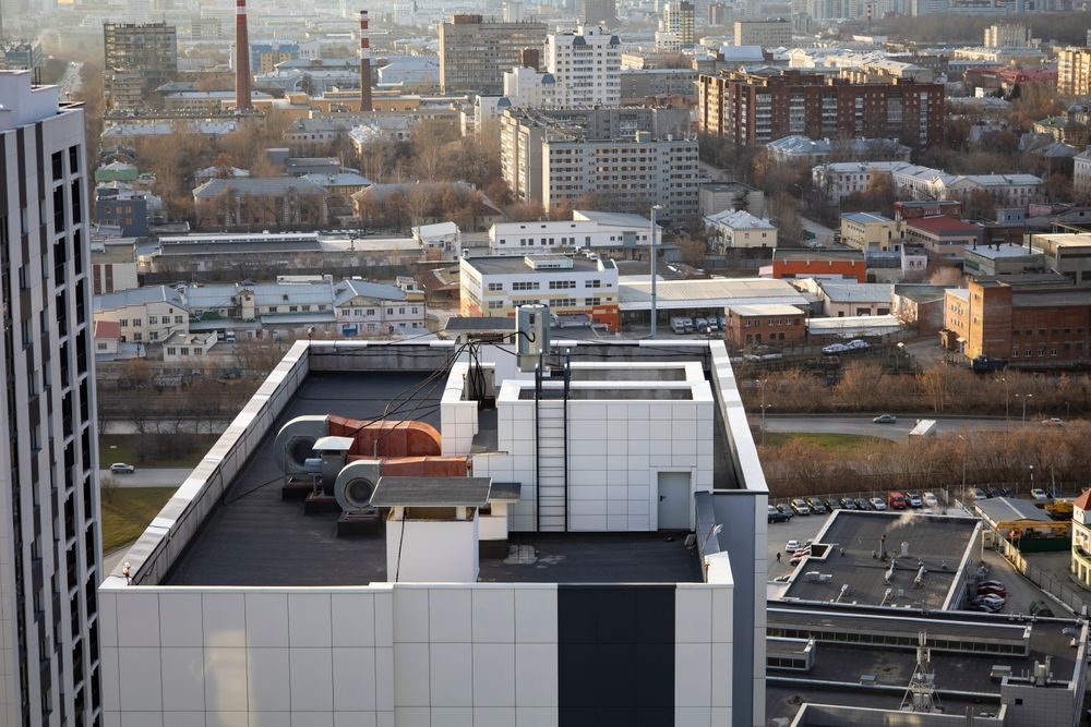 an aerial view of a city and a high rise with an AC system in the foreground.