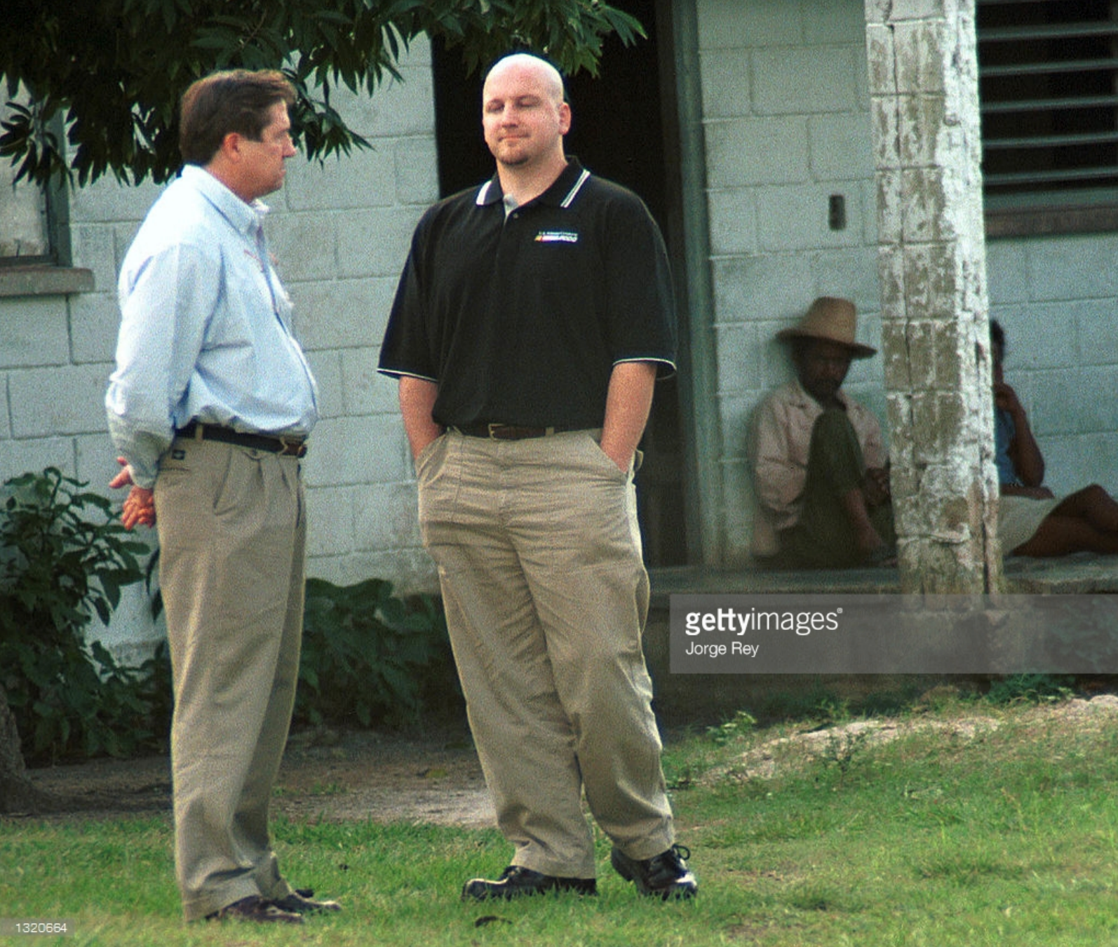 two men are standing in front of a building talking to each other .