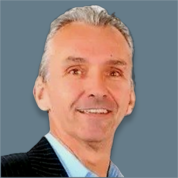 Homme souriant aux cheveux gris, portant une chemise bleue et un blazer noir à rayures.