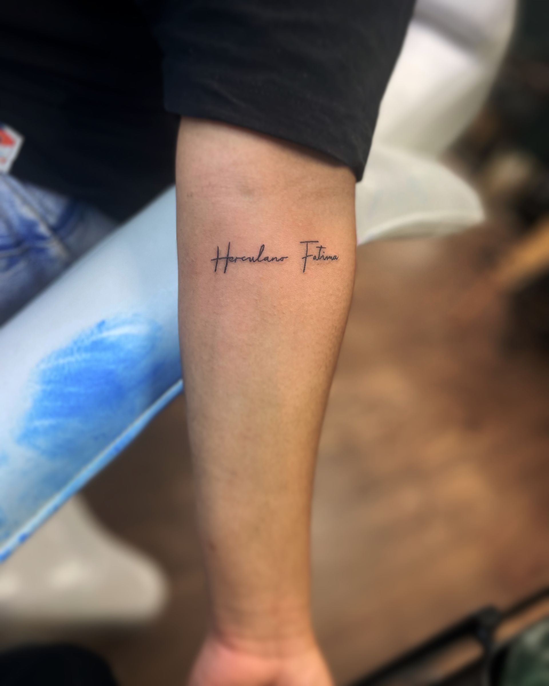 A close-up view of a forearm featuring a minimalist tattoo of the words 