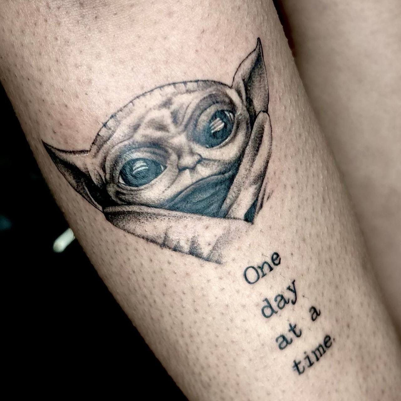A black-and-grey tattoo of Grogu from The Mandalorian, with the text