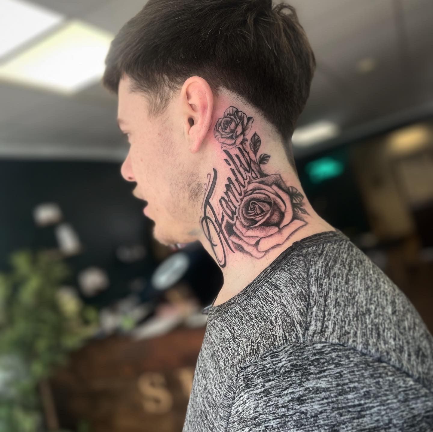 A side profile of a neck tattoo featuring two roses and the word 