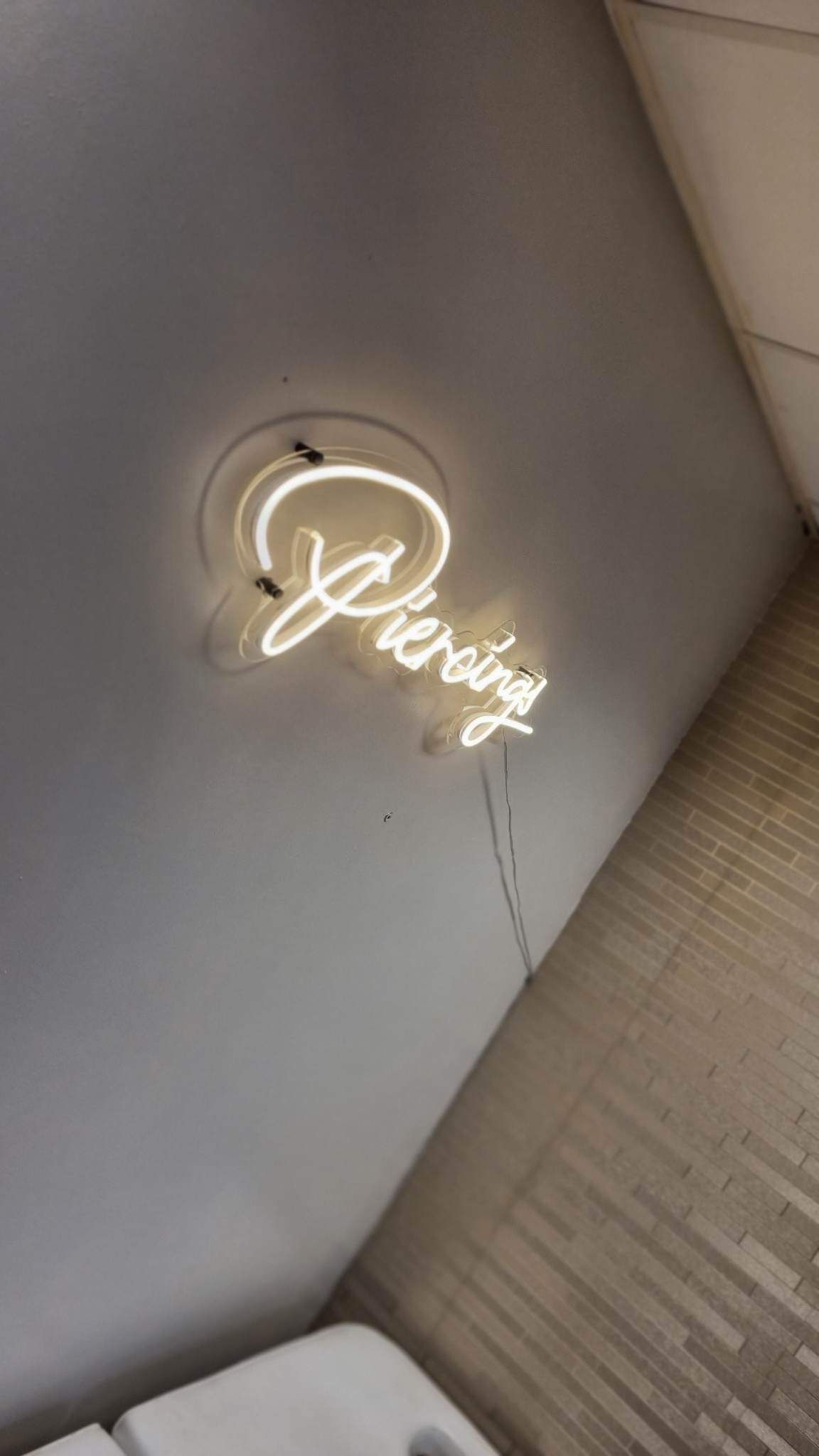 A white neon sign mounted on a grey wall that says 