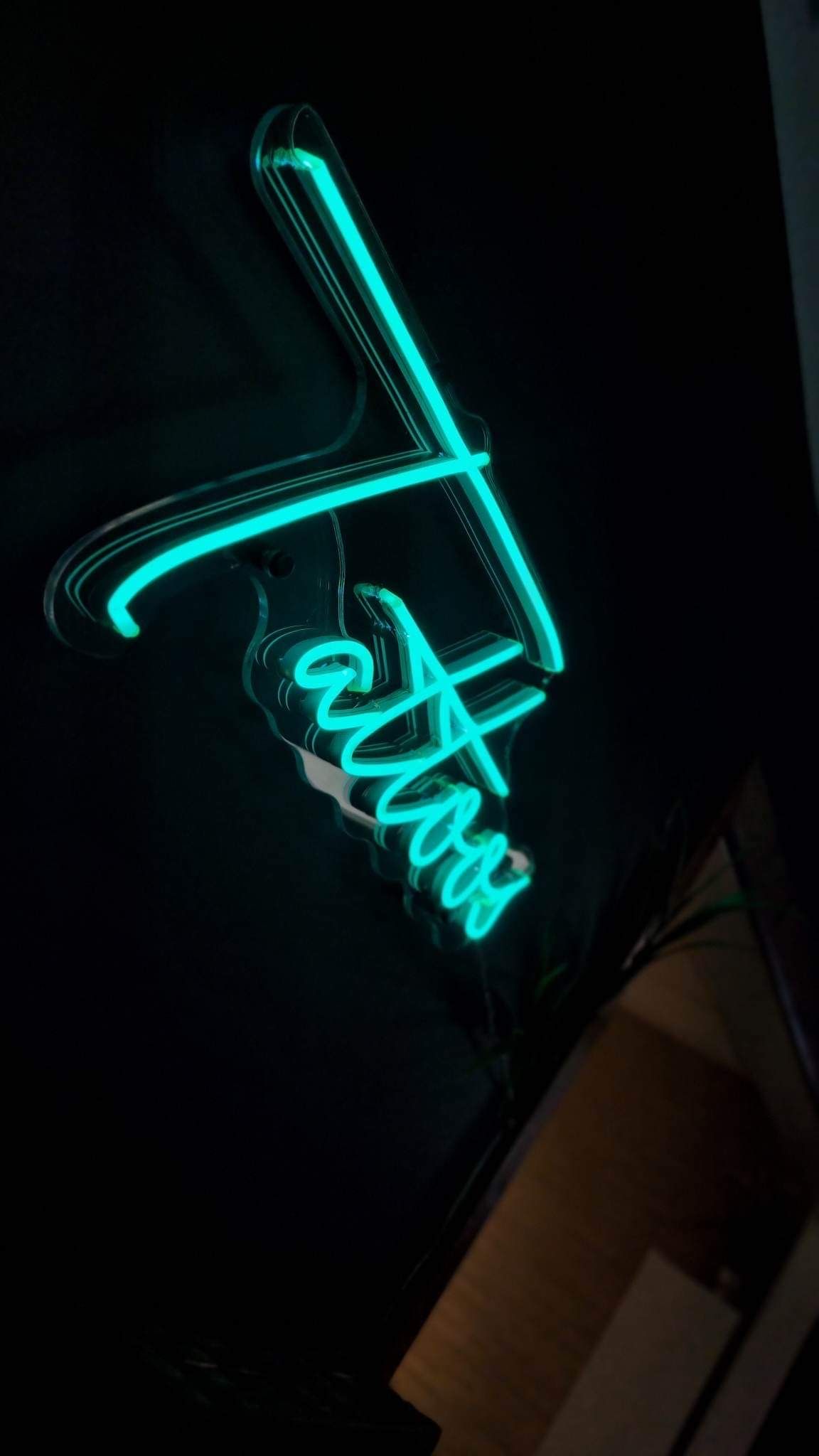 A glowing teal neon sign featuring the word 
