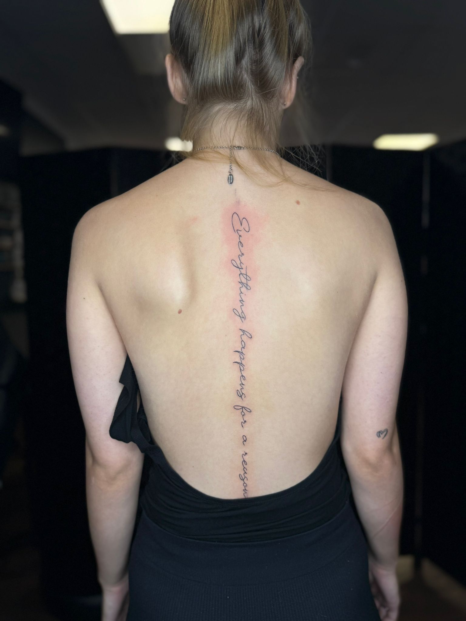 A person viewed from behind with a spine tattoo reading