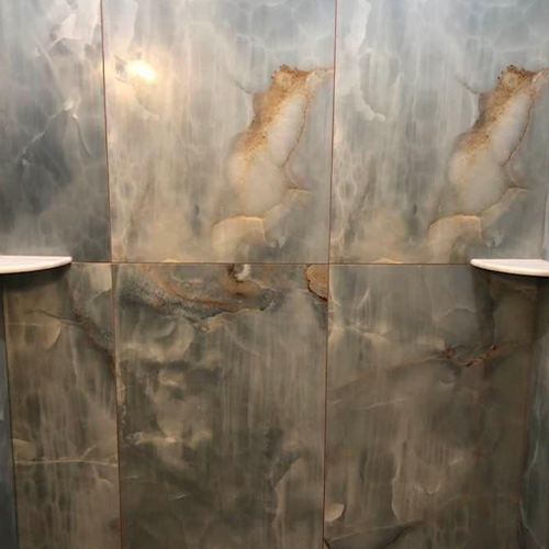 Wall tiles with a blue and grey veined marble pattern, featuring two white built-in corner shelves.
