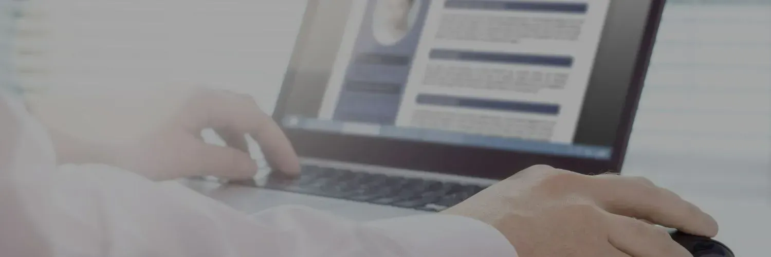 Hands typing on a laptop with a blurred analytics dashboard on the screen.