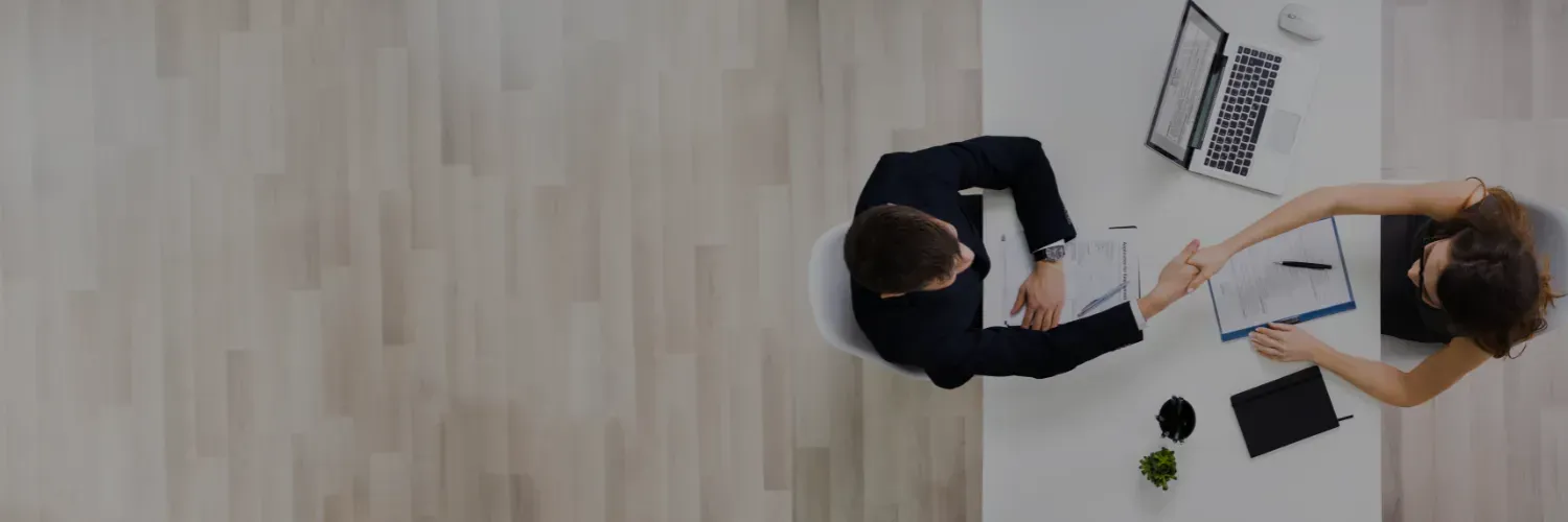 Overhead view of two people collaborating at a desk with a laptop, papers, and coffee cups