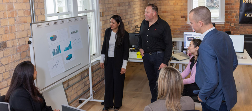 Three coworkers walking and talking in a modern office hallway