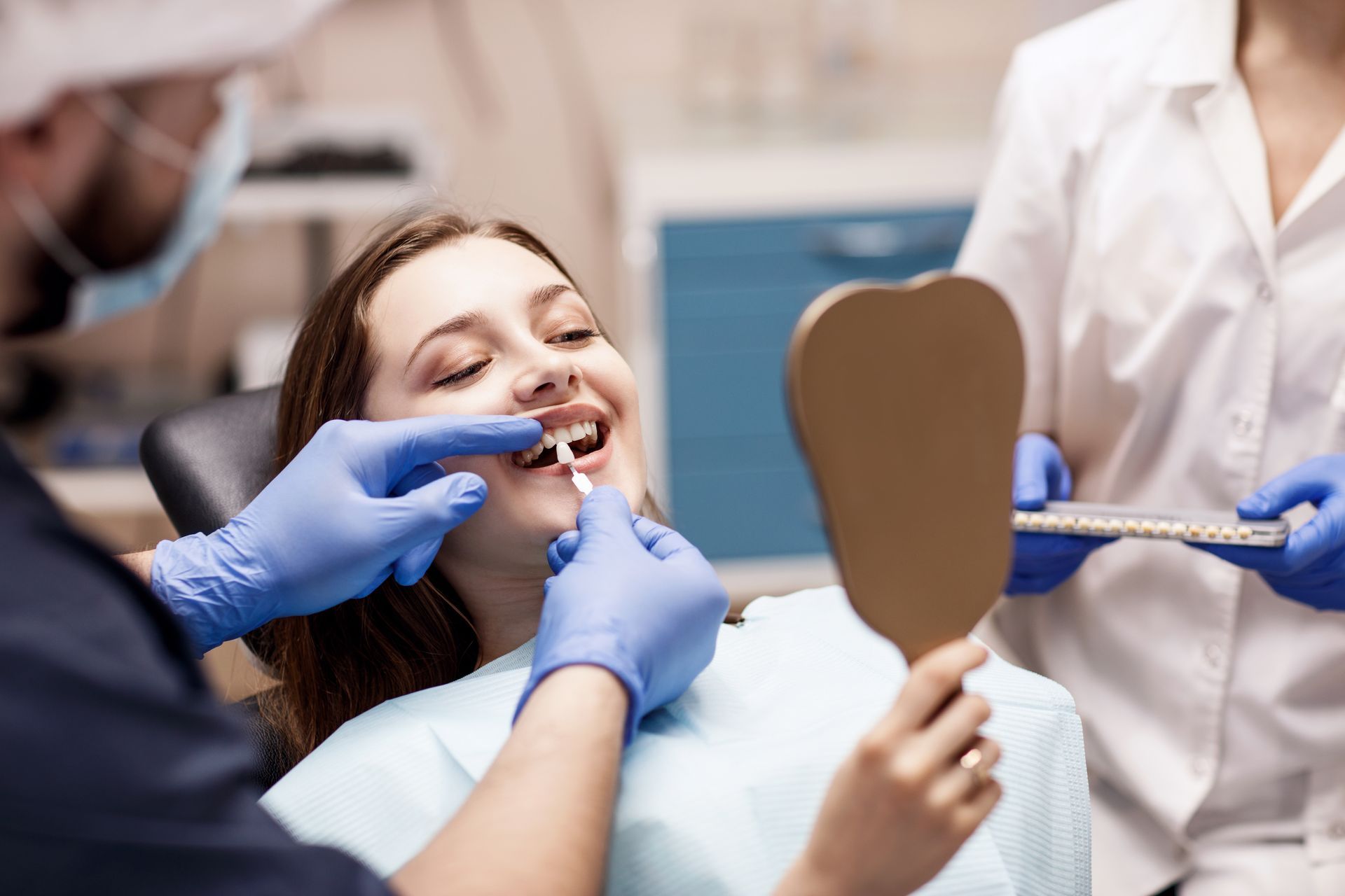 A female patient is being shown teeth shades with samples by a dentist and dental assistant. A female patient is being shown teeth shades with samples by a dentist and dental assistant.