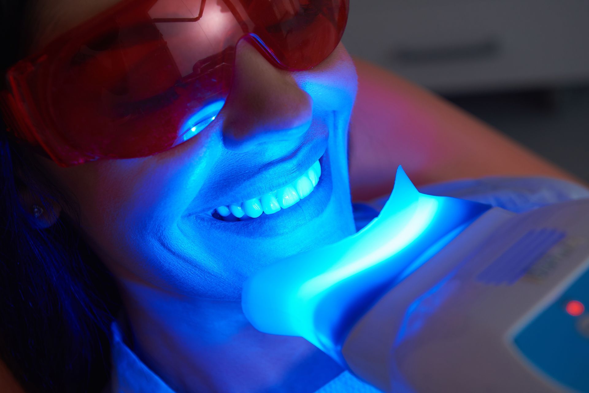 Close-up of happy lady doing dental whitening treatment in dental clinic.
