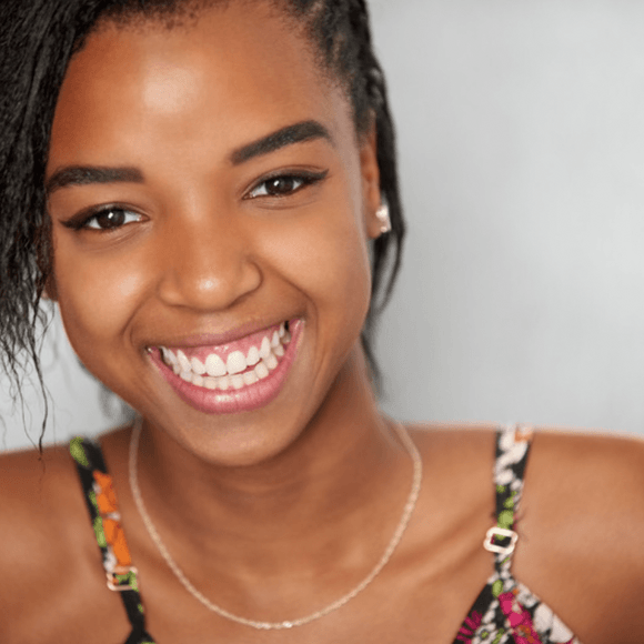 Smiling young Black woman wearing a floral top, looking at the camera.