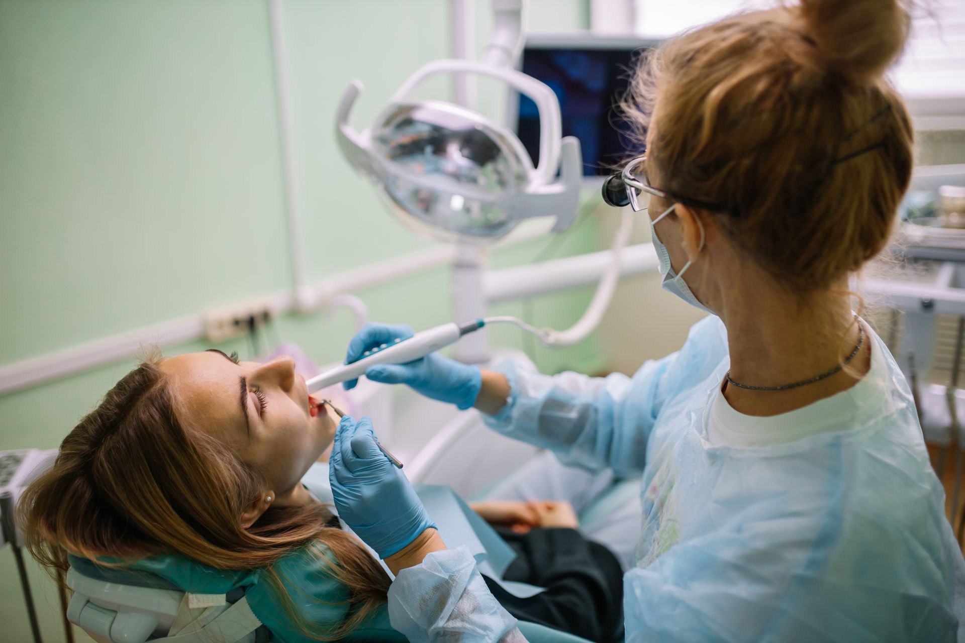 A female patient sitting in a chair with her mouth open as a family dentist conduct examination.