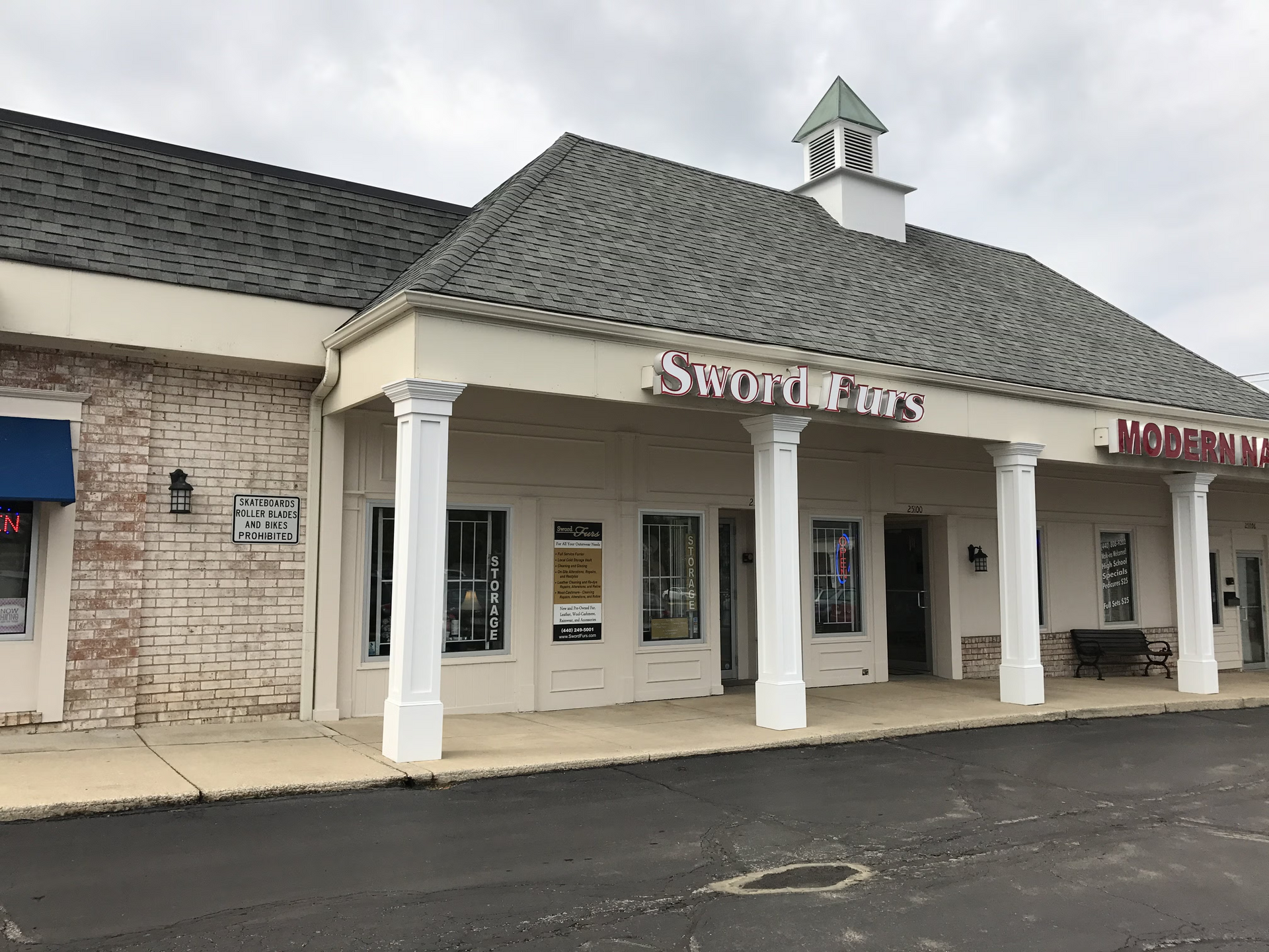 Shopping center storefront with white columns and a small cupola, seen from the parking lot.