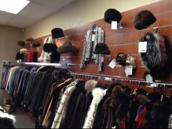 Wall of hats, scarves, and fur coats displayed in a clothing store.