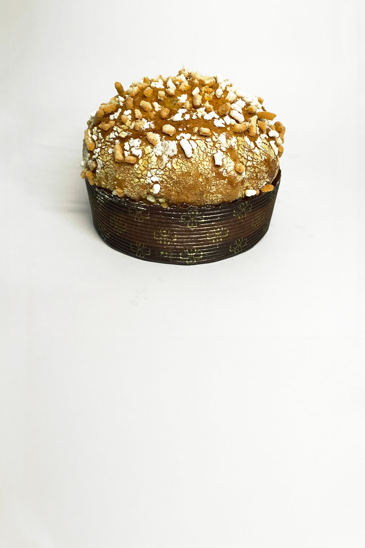 un panettone con sopra scaglie di castagne su una superficie bianca.
