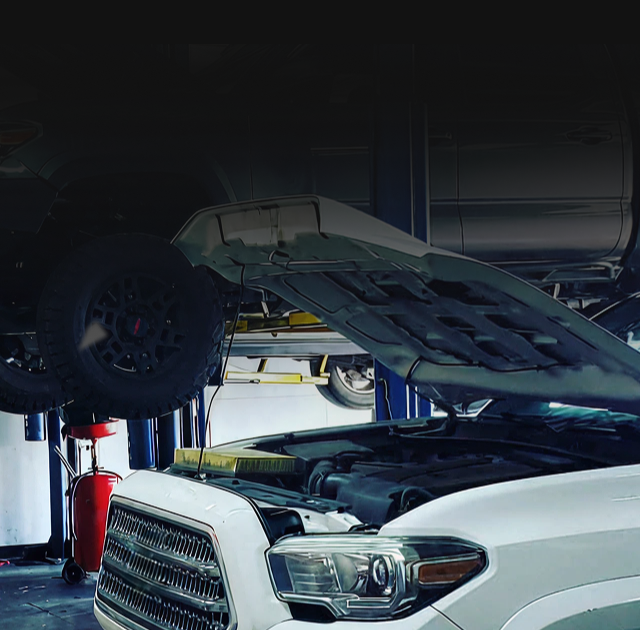 White SUV in a garage with its hood open, parked beside tools and equipment | 4G Automotive and Transmission