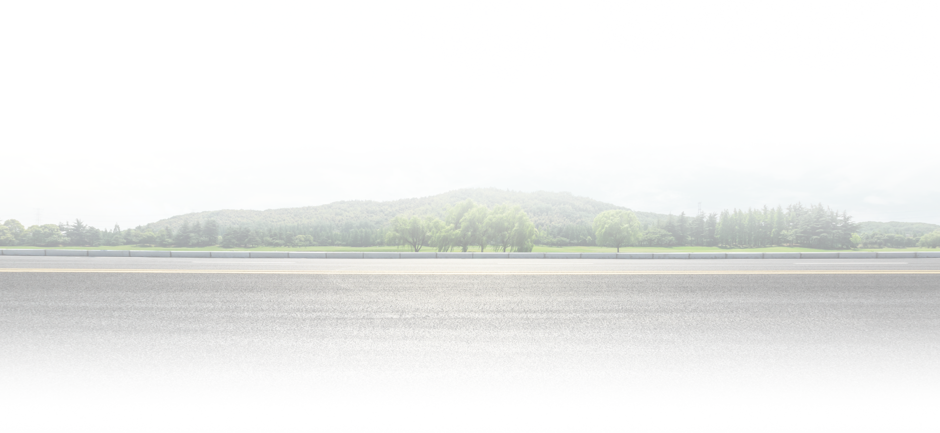 Hazy panoramic landscape with a calm river and low green hills under a bright sky | 4G Automotive and Transmission