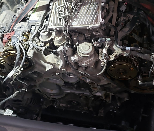 Close-up of a car engine with exposed belts, pulleys, and hoses in a repair bay | 4G Automotive and Transmission