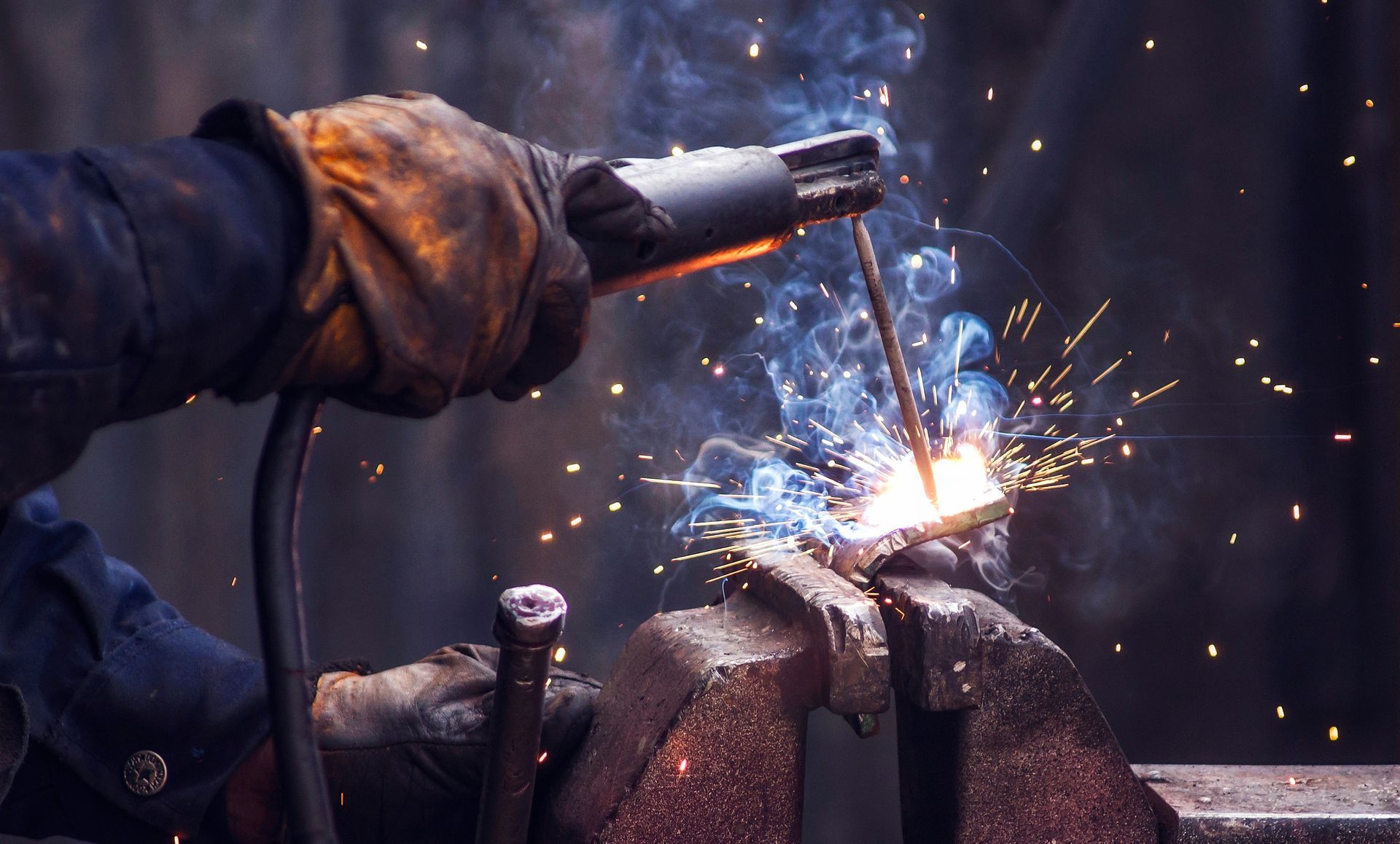 A man is welding a piece of metal with a welding machine.